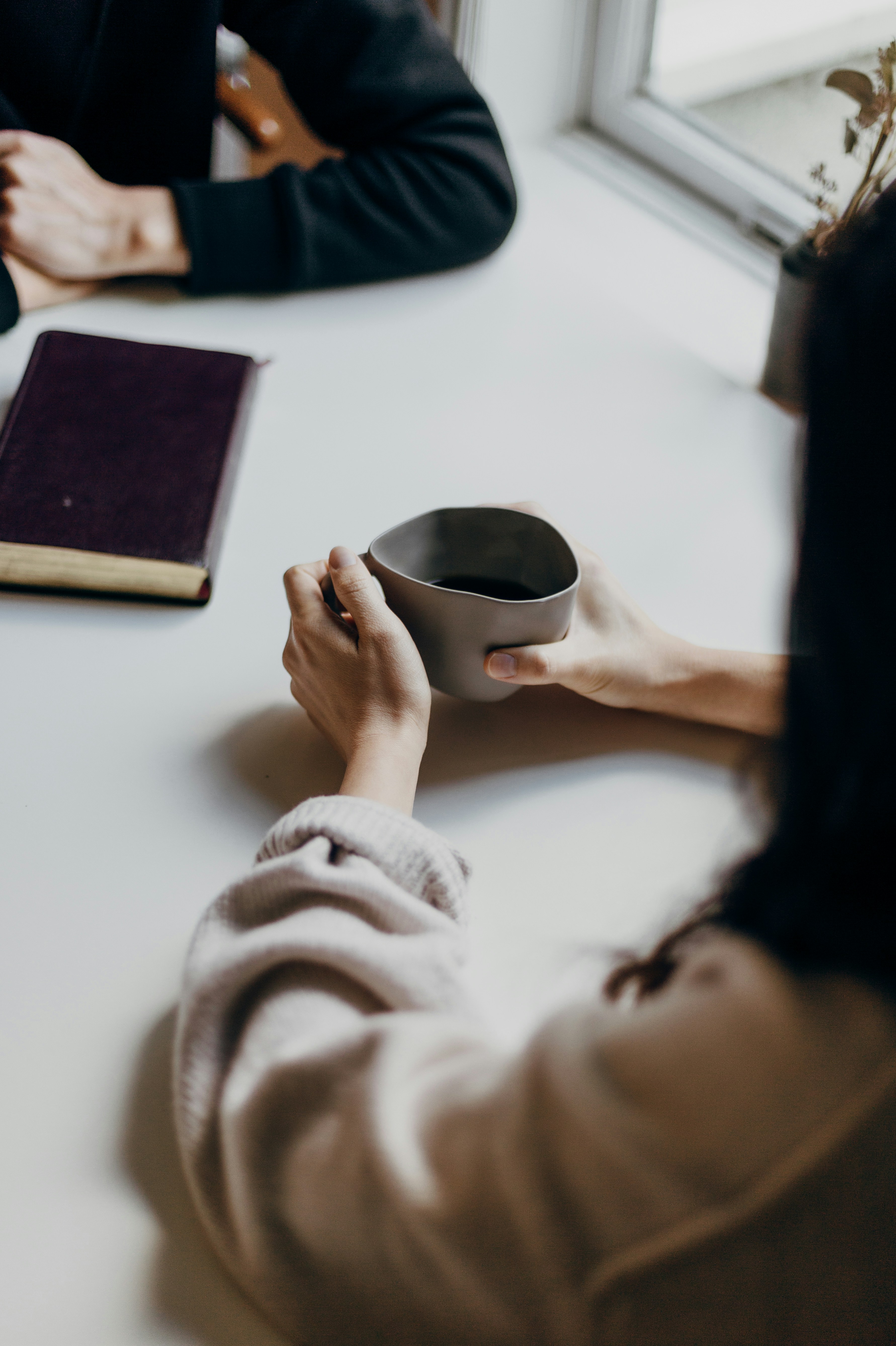 brazos de dos personas sobre una mesa un de ellas con una taza de te y la otra con los brazos cruzados en una terapia de psicologia para ansiedad 